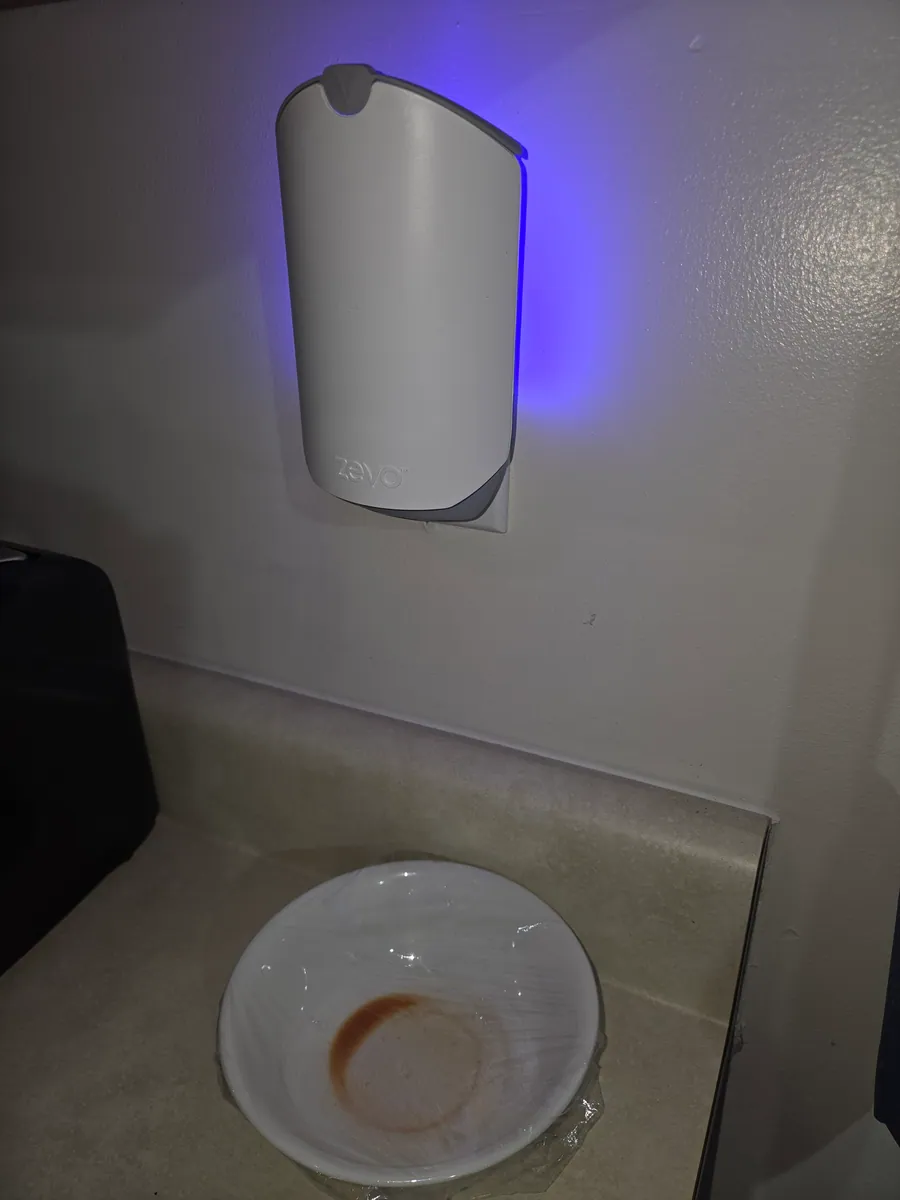 Jason's Zevo Smart Light glowing in a wall outlet above a kitchen counter with a cellophane-covered vinegar bowl below